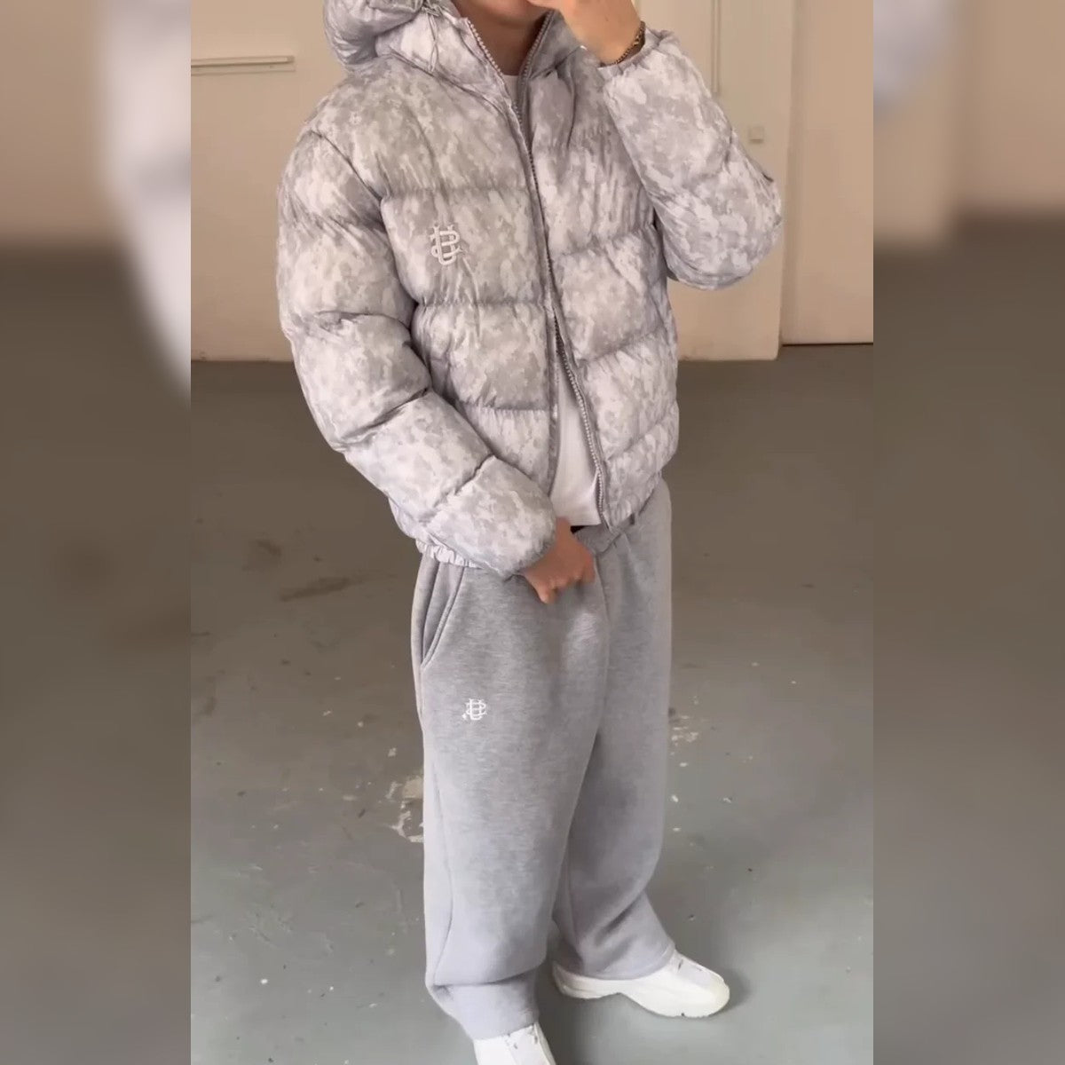 Doudoune courte à capuche camouflage gris portée avec un jogging gris