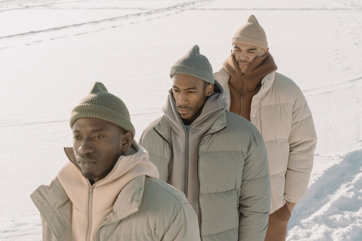 Trois hommes en doudounes et bonnets dans la neige