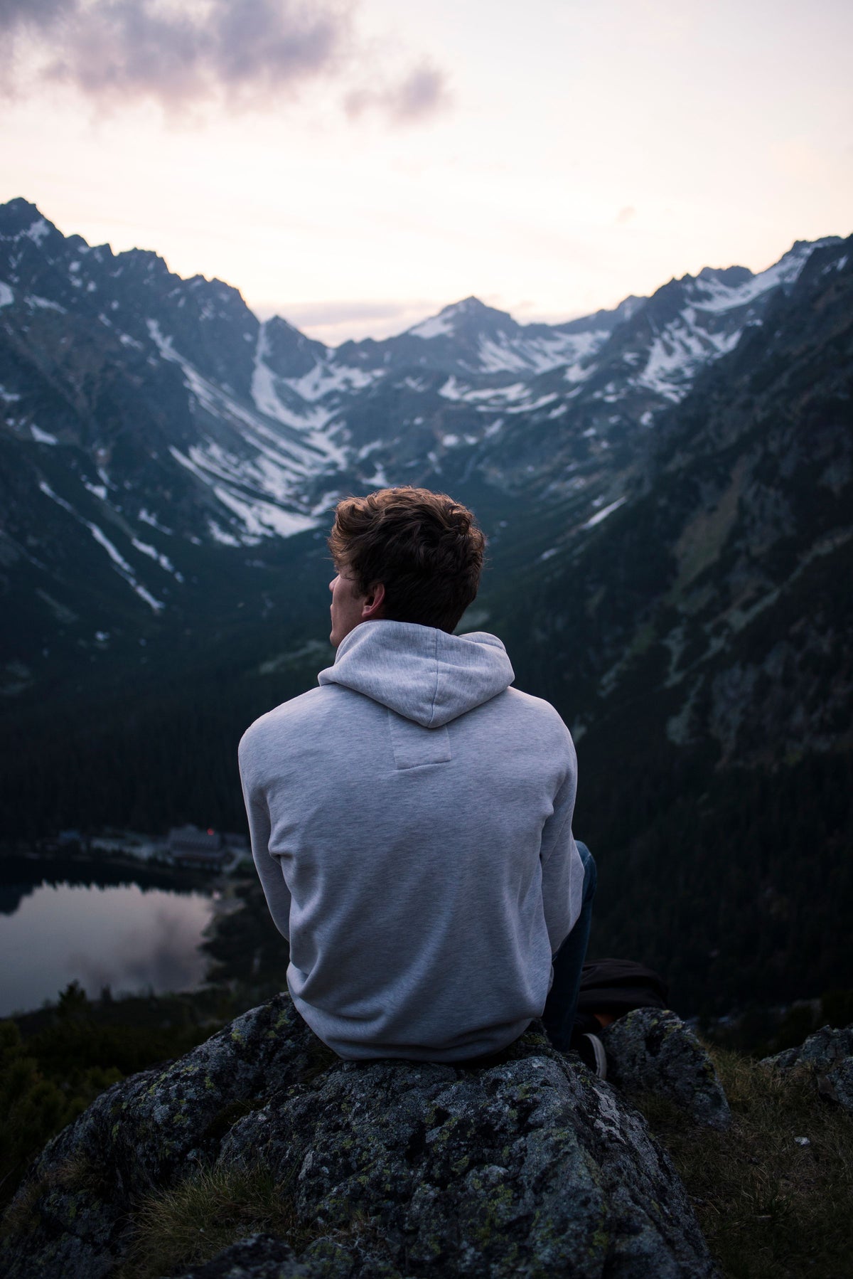 Homme en sweat à capuche face aux montagnes enneigées